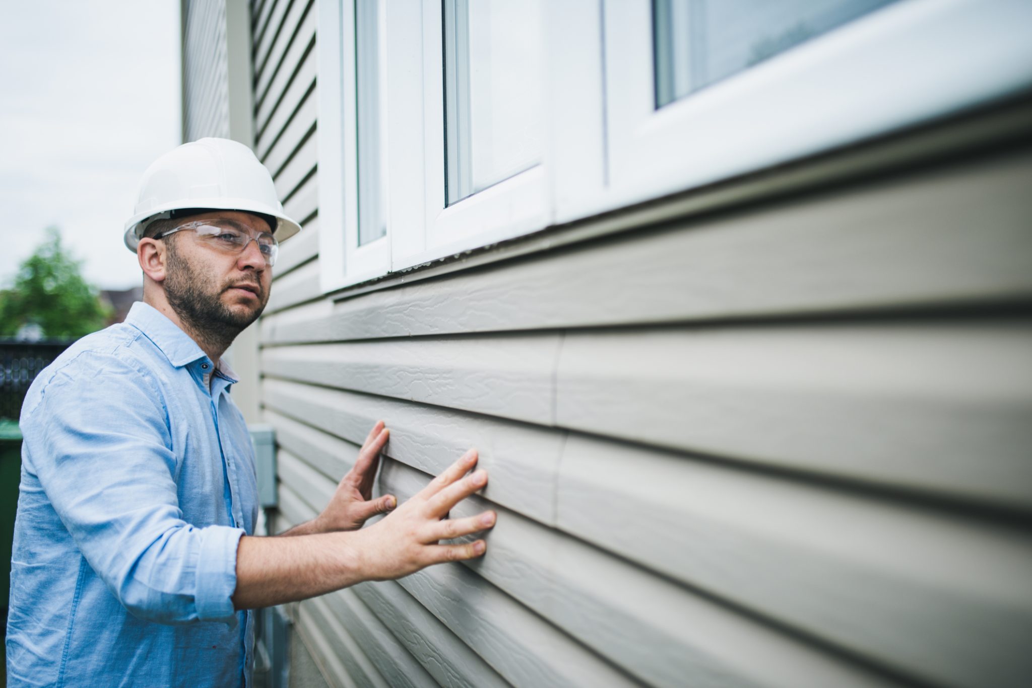 Home inspector observing siding on a house