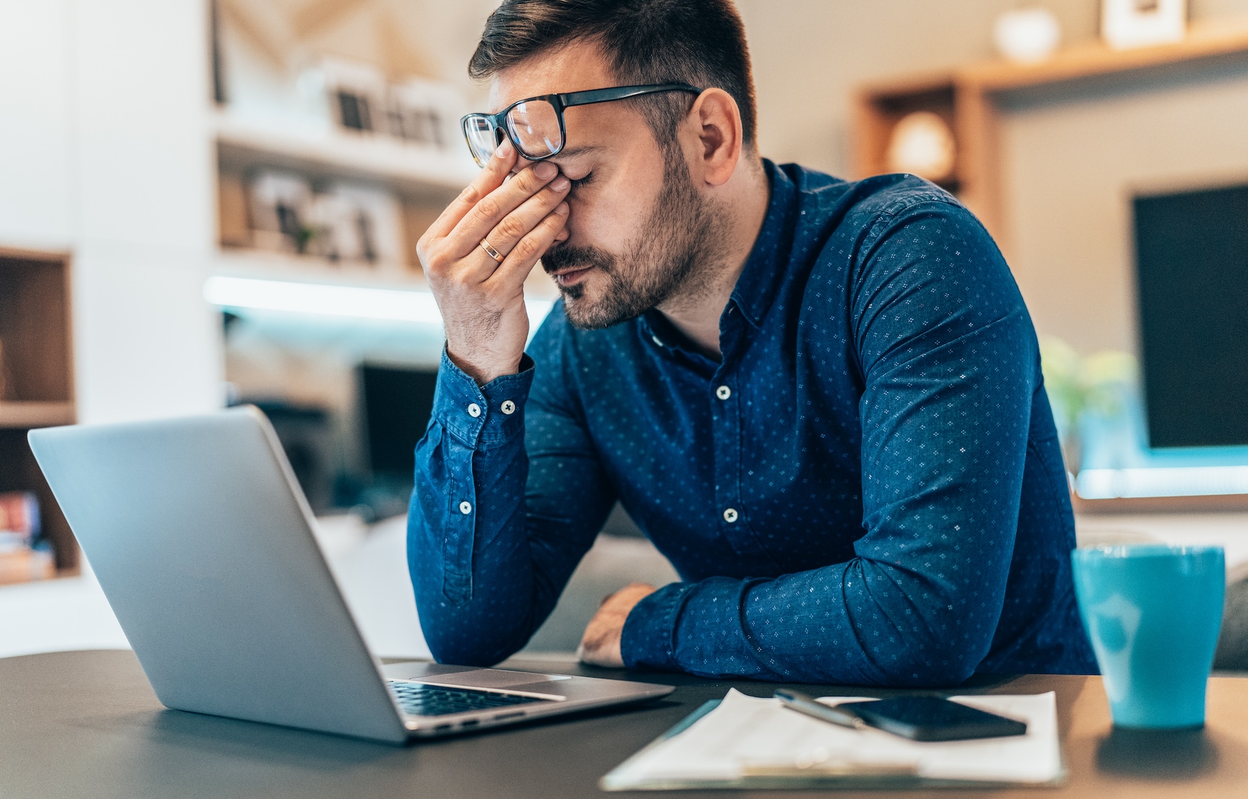 Frustrated male real estate agent working from home on laptop